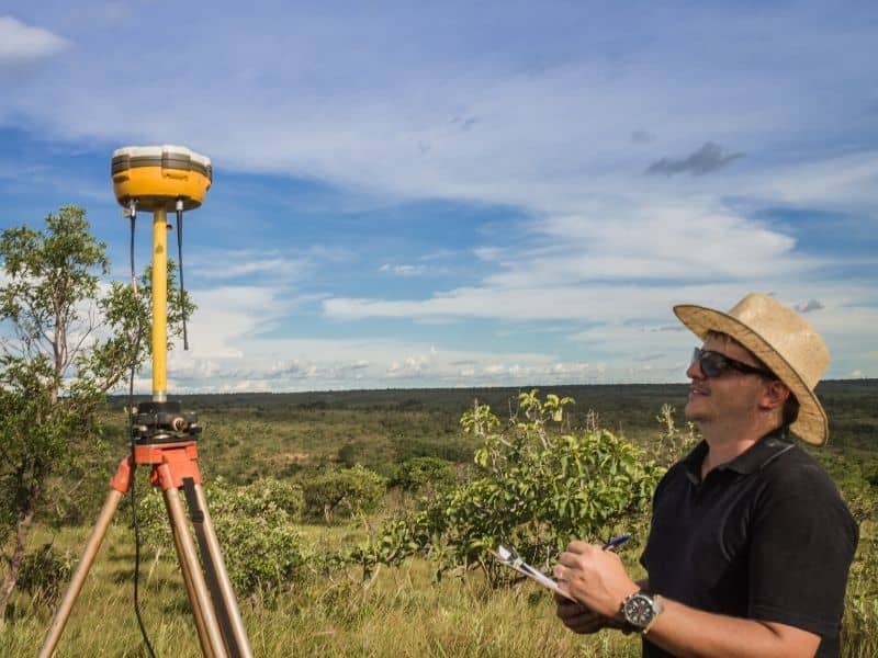 Surveyor measuring open desert terrain with topographic survey equipment before site grading and elevation planning.